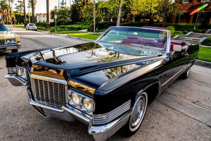 Black 1970 Cadillac DeVille convertible with a red interior, roof down, on a Los Angeles street