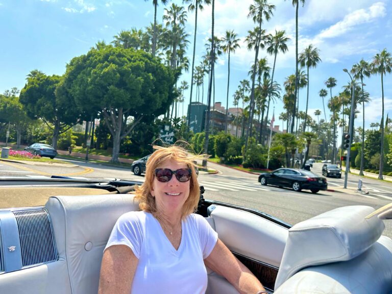Smiling guest in the back seat of the convertible on a sunny Beverly Hills street