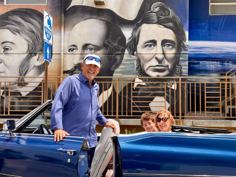 Guests in the blue Cadillac convertible in front of a large street mural in Venice
