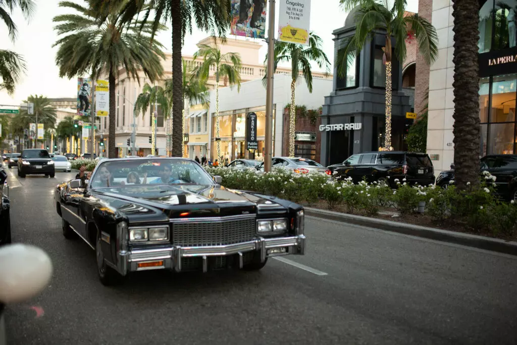 Black 1970s Cadillac Eldorado convertible driving down palm-lined Rodeo Drive in Beverly Hills