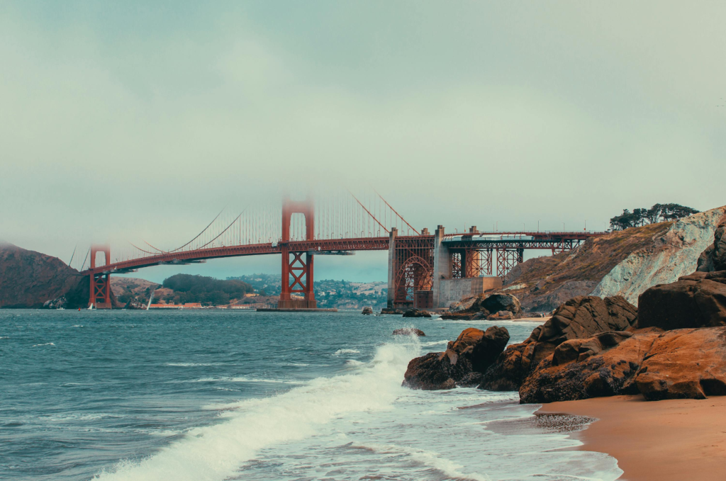 Golden Gate Bridge seen from a rocky beach with waves rolling in