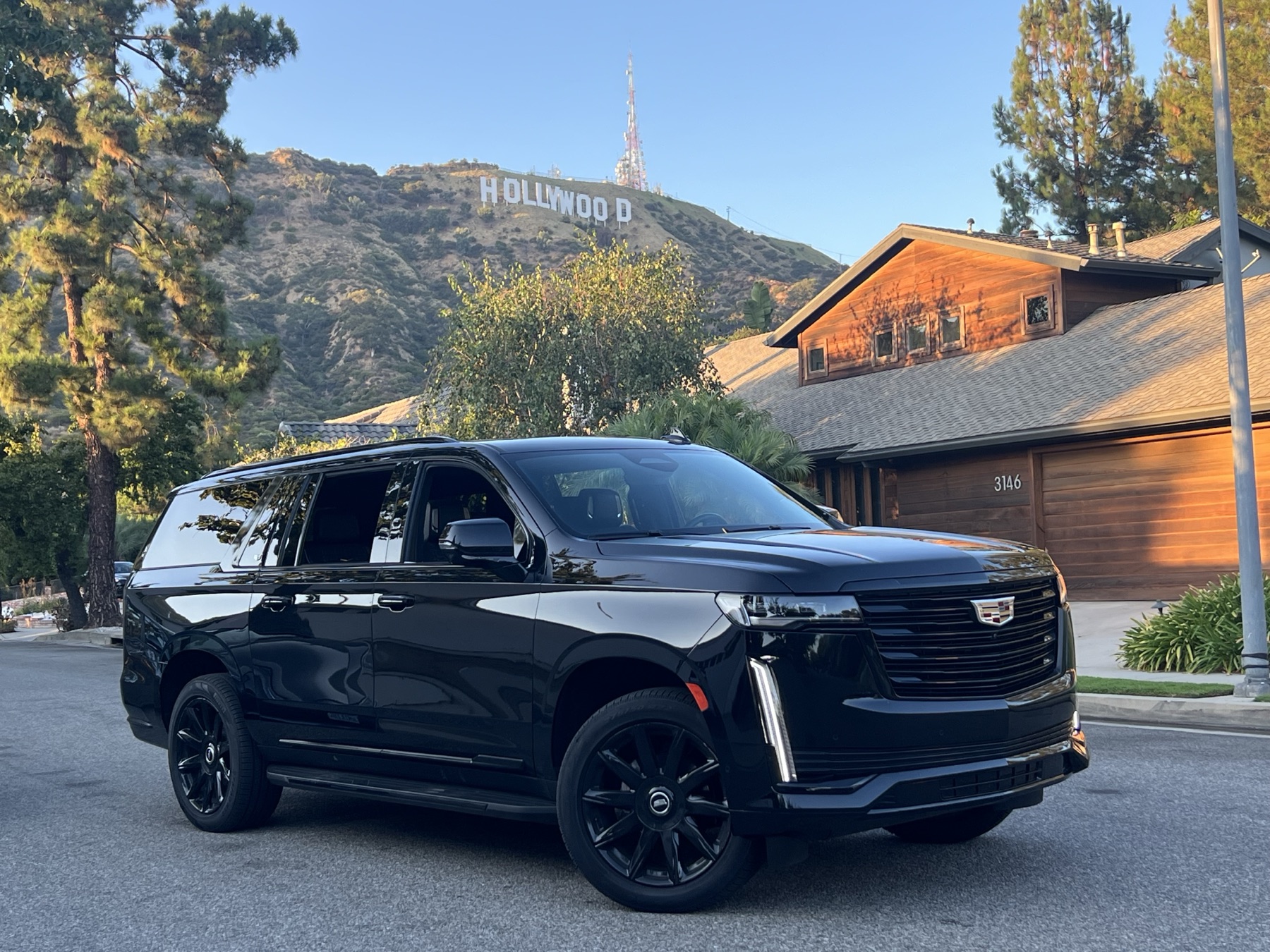Black Cadillac Escalade Luxury SUV With The Hollywood Sign Behind It On A Private Los Angeles Tour From Anaheim